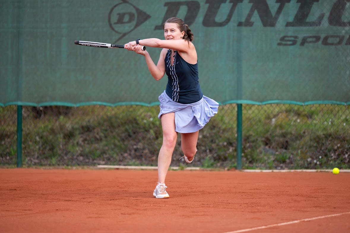 Elena hitting a backhand groundstroke on a clay court